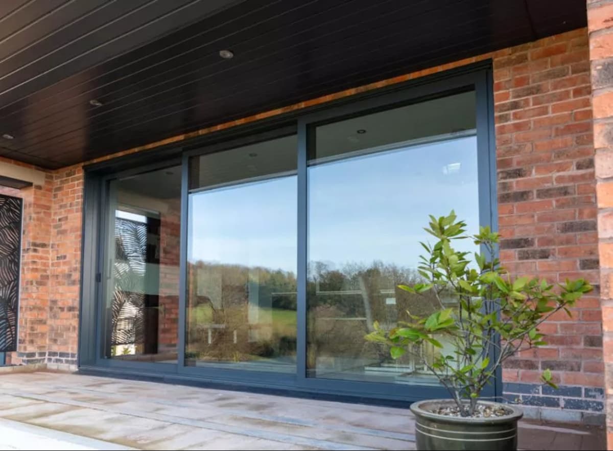 A Patio triple track anthracite door on a brick building