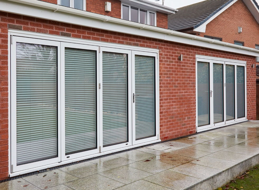 Blinds down and closed Supreme 3.6M White aluminium Bifold doors view from the garden