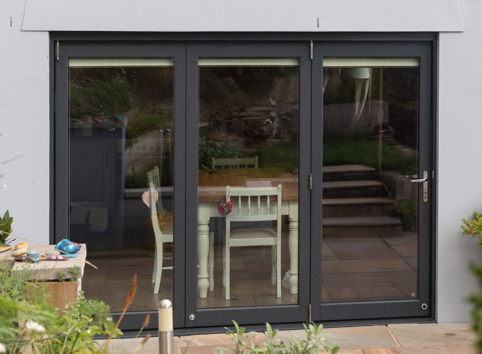 Outside closed Ultra 2.7M grey bifold doors with a view into the kitchen